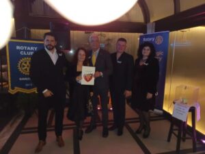 Gruppo di soci Rotary riuniti davanti ai banner ufficiali del Rotary Club durante un incontro conviviale e istituzionale.