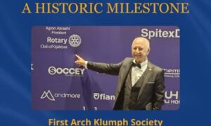 Poster commemorativo blu con testo dorato e una foto del Dr. Agron Abrashi che sorride e punta a un logo del Rotary, celebrando la sua iscrizione alla Arch Klumph Society.