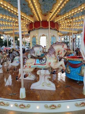 Giostra d'epoca con cavalli di legno illuminata a festa, simbolo di meraviglia, memoria condivisa e Diplomazia dei Sentimenti negli spazi pubblici.
